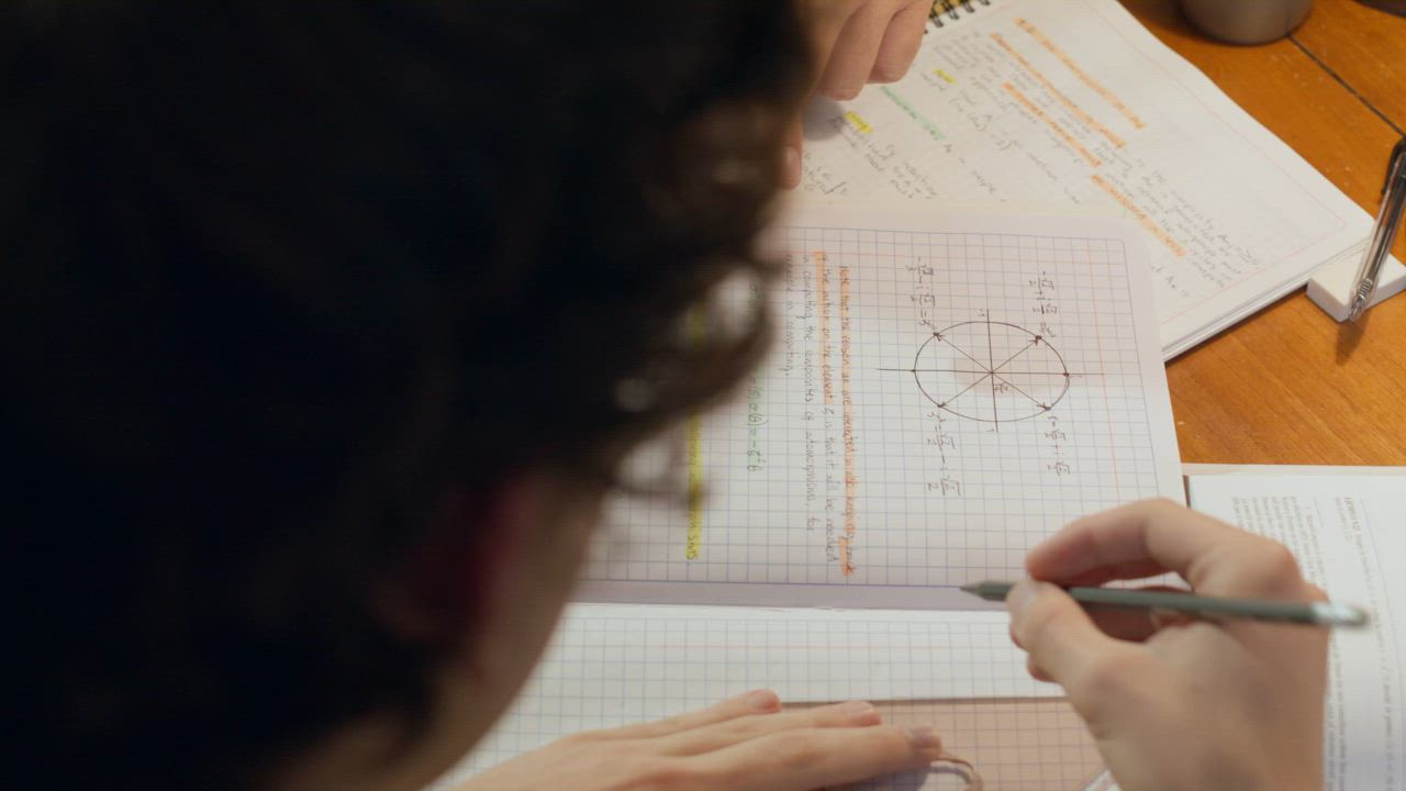 A teacher pointing to a chart on a student's notebook